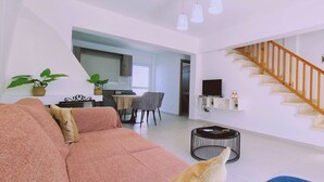 Un saló modern amb un sofà, una zona de menjador i una escala.