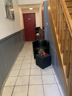 Stylish hallway with a red door, black chair, and bicycle, leading to a cozy space.