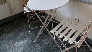 A corner room with a white round table and two white chairs with metal frames. - Small room near Belgium (Halluin)