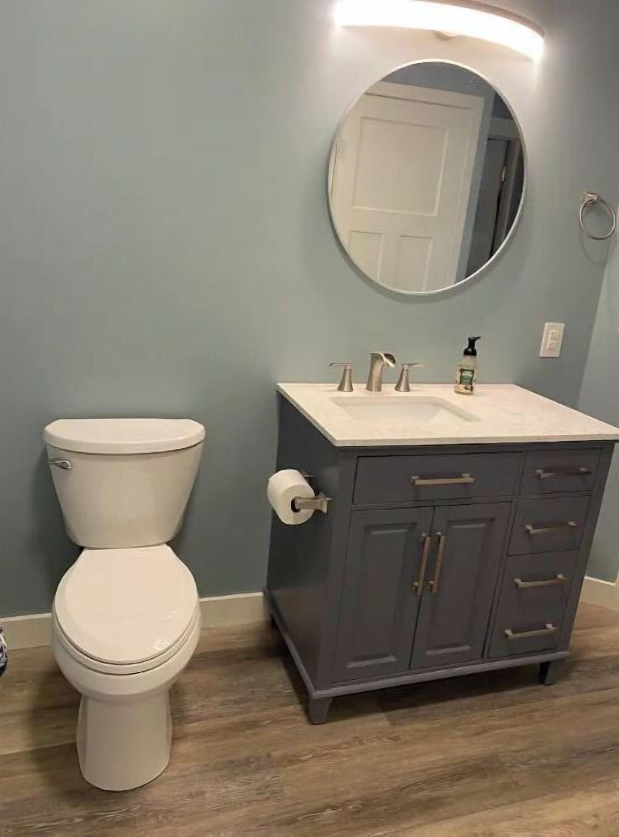 A bathroom with a toilet, a sink, and a cabinet.