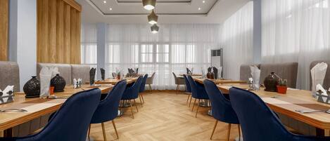 Un salón de conferencias con una larga mesa, sillas azules y suelo de madera.