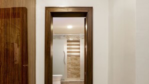 A hallway leading to a bathroom with a toilet and a shower area. - Aveon Hotel (Abuja)