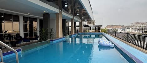 Una piscina interior con agua cristalina y azul, rodeada por una solana con baldosas y una barandilla.