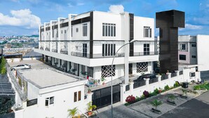 A modern multi-story building with a flat roof, large windows, and a parking area with cars. - Aveon Hotel (Abuja)
