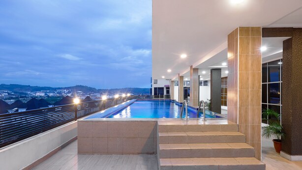 A rooftop pool with a view of a cityscape at dusk. - Aveon Hotel (Abuja)
