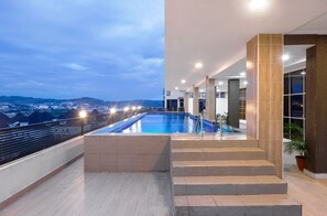 A rooftop pool with a view of a cityscape at dusk. - Aveon Hotel (Abuja)