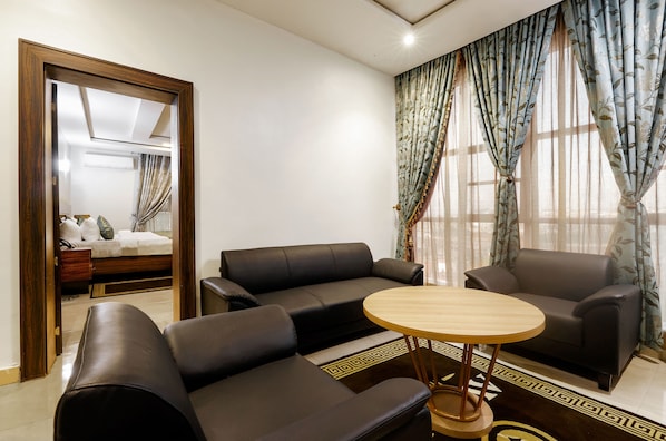 Una sala de estar moderna con un sofá, sillones y una mesa de centro redonda.