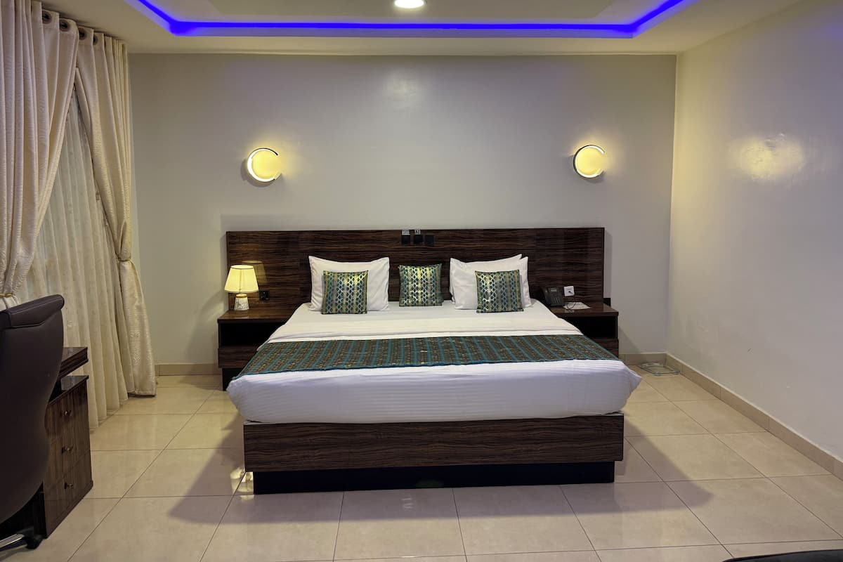 Habitación de hotel moderna con una cama grande, cabecera de madera e iluminación LED azul en el techo.