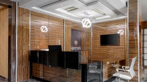 A reception desk with a wooden panel design, a black counter, and a white chair. - Aveon Hotel (Abuja)