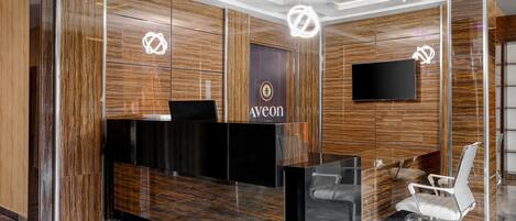 A reception desk with a wooden panel design, a black counter, and a white chair.