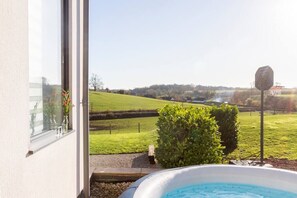 Une vue depuis une fenêtre donnant sur un paysage verdoyant, avec une piscine au premier plan.