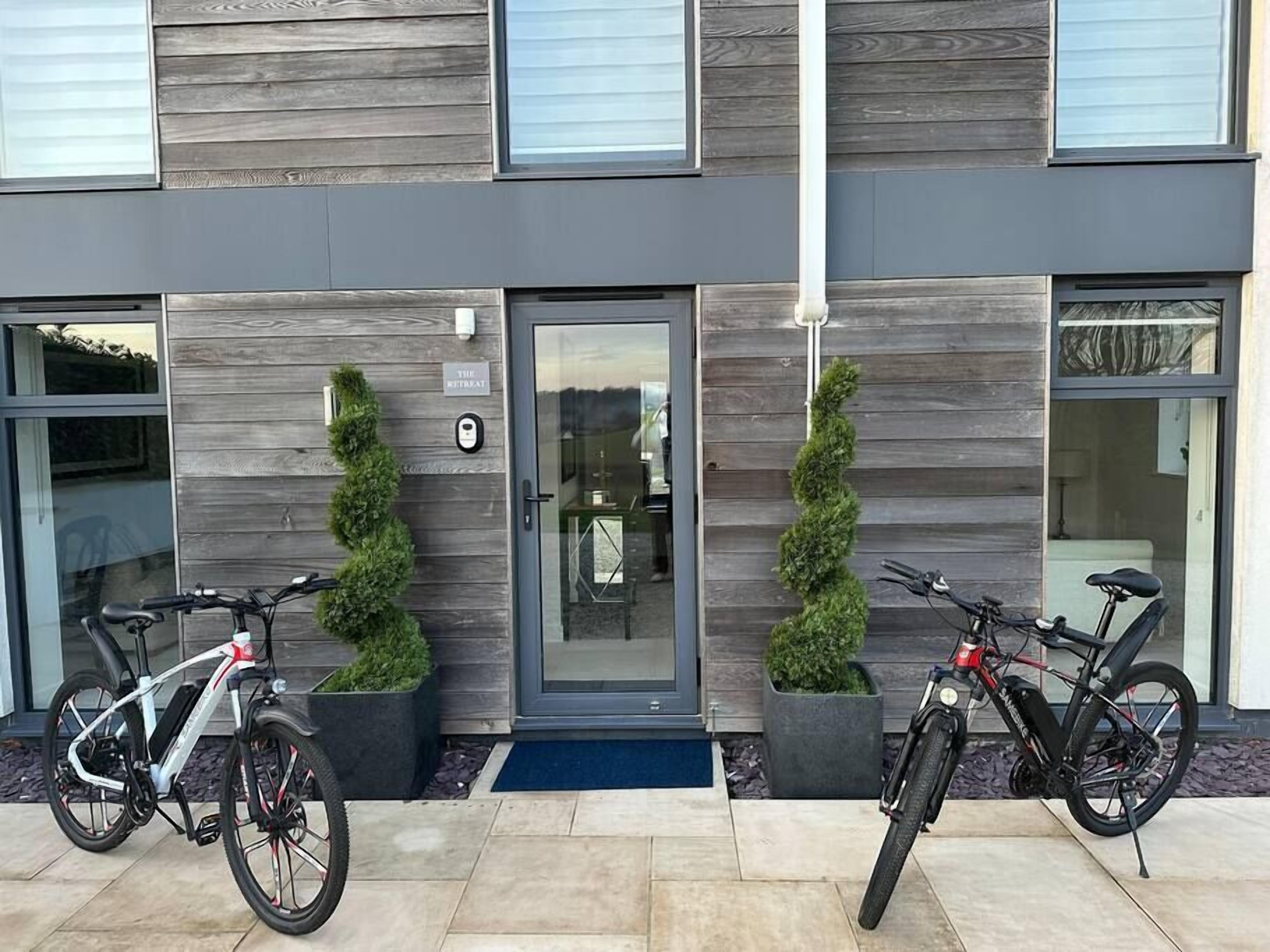 En moderne bygning med en grå facade, en glasdør og to cykler foran.