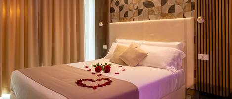Una cama impecablemente arreglada con una decoración de rosa en forma de corazón, un cabecero moderno y un muro con estampado geométrico.