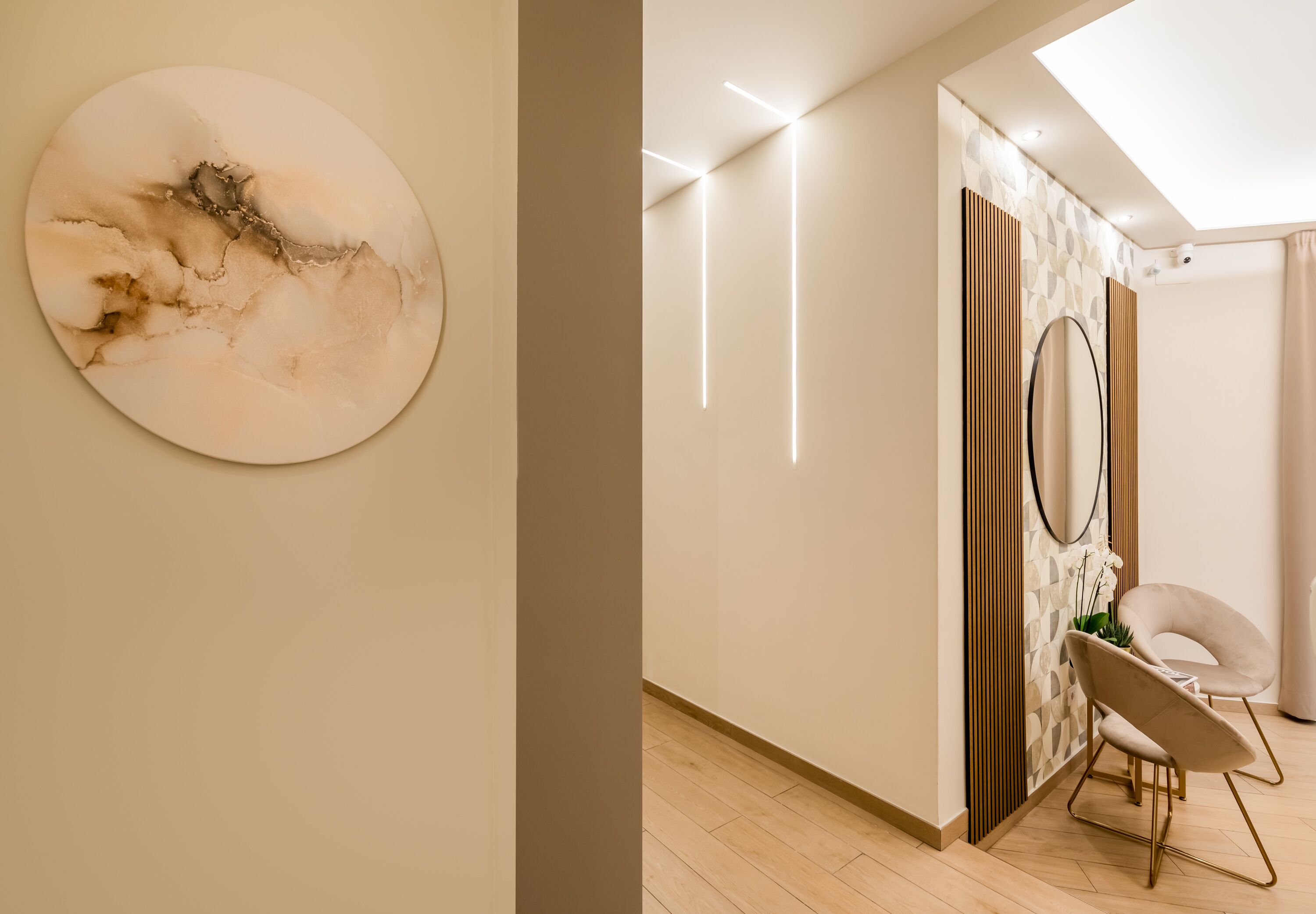 A modern interior with a minimalist design, featuring a round abstract painting, a sleek chair, and a geometric patterned wall.