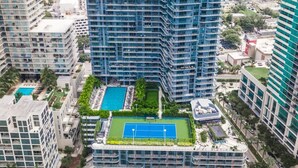 A high-rise building with multiple balconies, a rooftop pool, and a tennis court. - HYDE MIDTOWN RESIDENCES SPECTACULAR CORNER 2BR (Miami)