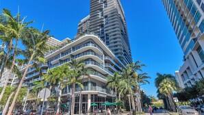 A modern hotel with multiple balconies, palm trees, and a Starbucks on the ground floor. - HYDE MIDTOWN RESIDENCES SPECTACULAR CORNER 2BR (Miami)