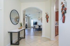 A modern kitchen with wooden cabinets, a dining area with a round table and chairs, and a living room with a TV and seating area. - Beautiful 3 bedrooms Condo at Vista Cay with lake view. 
Refurbished July 2024 (Orlando)