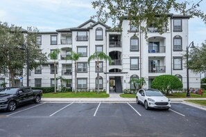 A multi-story residential building with a central entrance, balconies, and a parking lot. - Beautiful 3 bedrooms Condo at Vista Cay with lake view. 
Refurbished July 2024 (Orlando)