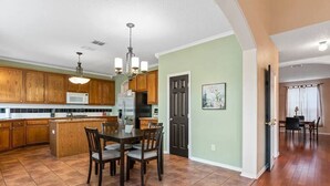 A spacious kitchen with wooden cabinets, a central island, and a dining area with a chandelier.