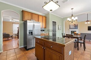 Una cocina con armarios de madera, un refrigerador de acero inoxidable y una isla de vidrio.