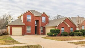 A two-story brick house with a garage, a front entrance, and a driveway.