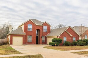 A two-story brick house with a garage, a front entrance, and a driveway.