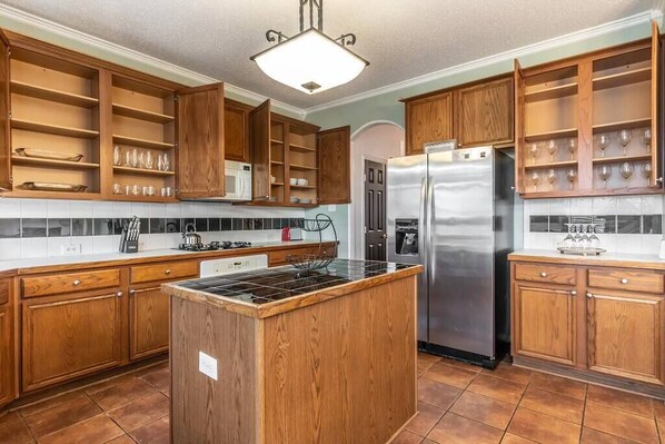 Una cocina con armarios de madera, un refrigerador de acero inoxidable y una isla central.