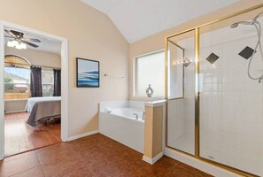 A bathroom with a bathtub, a shower, and a window.