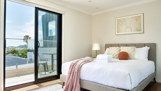 A bedroom with a bed, a nightstand, a lamp, a window with a view, and a painting on the wall. - Balmain Family Tranquility - Harbour Views (Balmain East)