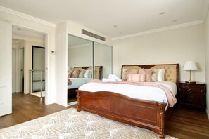 A bedroom with a wooden bed, a mirror, a nightstand, and a patterned rug.