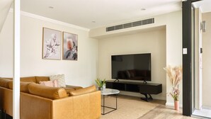 A living room with a sofa, a flat-screen TV, a small table, and wall art. - Balmain Family Tranquility - Harbour Views (Balmain East)