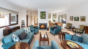 A spacious living room with a fireplace, blue sofas, and a dining area.