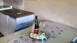 A kitchen with a sink, a dining table with a placemat, a bottle of wine, and a decorative wall with the word 'Natura'.