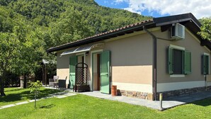A house with a patio, green shutters, and a mountain backdrop.