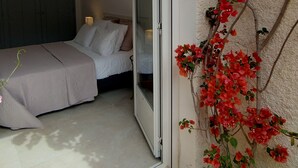 A bedroom with a sliding glass door leading to a balcony with red flowers and green plants. - Gîte LES OLIVIERS located in a quiet area among the pines, close to the beaches (Béziers)