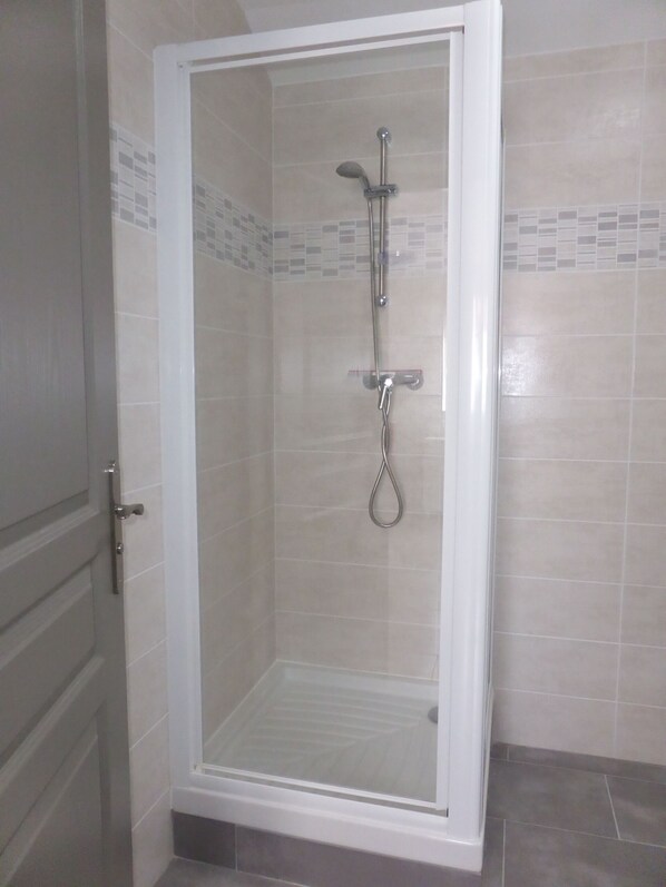 Una ducha con cerramiento de vidrio, cabezal de ducha manual y cabezal de ducha fijo.
