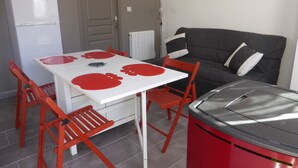 Un espacio habitable compacto con una mesa de comedor, sillas, un sofá y una kitchenette.