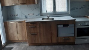 Una cocina con armarios de madera, encimera de mármol, lavavajillas empotrado y una estufa.