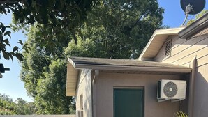 A residential property with a paved patio, a green door, and an air conditioning unit mounted on the exterior wall. - Cheerful 1 bedroom guest suite with pool and yard (Spring Hill)