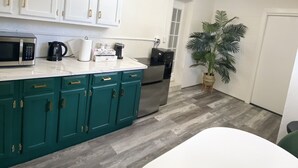 A modern kitchen with white cabinets, a teal countertop, a microwave, a coffee maker, and a refrigerator. - Cheerful 1 bedroom guest suite with pool and yard (Spring Hill)