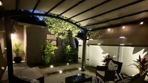 An outdoor patio area with a covered seating arrangement, a patterned rug, and potted plants. - Cheerful 1 bedroom guest suite with pool and yard (Spring Hill)