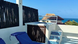 A balcony with two sun loungers, a small pool area, and a view of the ocean. - Casa Paraiso Caribe - stunning views! (Isla Mujeres)