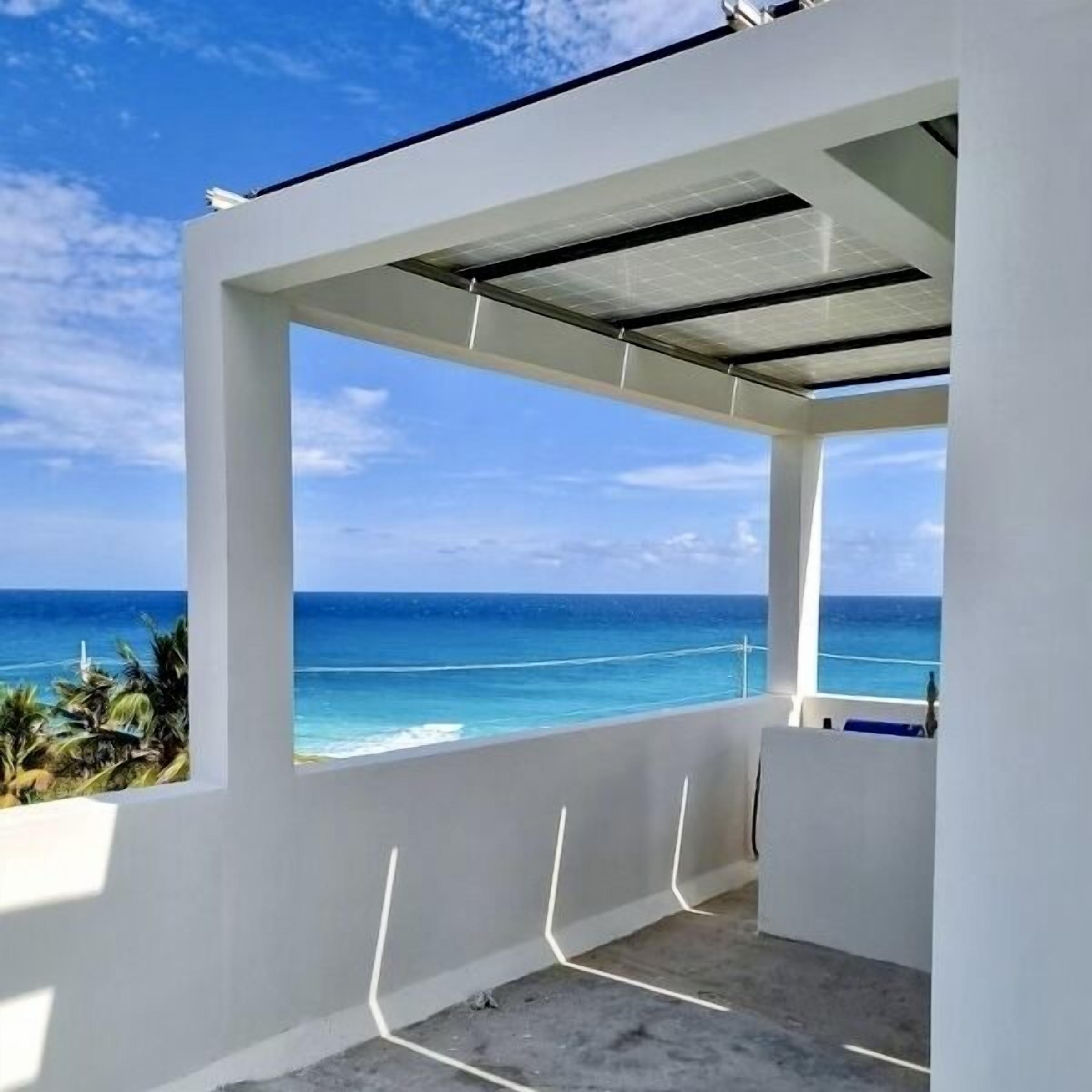 Ein moderner Balkon im Freien mit freiem Blick auf das Meer und eine tropische Landschaft.