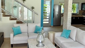 A modern living room with a white sofa, a coffee table, and a ceiling fan. - Casa Paraiso Caribe - stunning views! (Isla Mujeres)