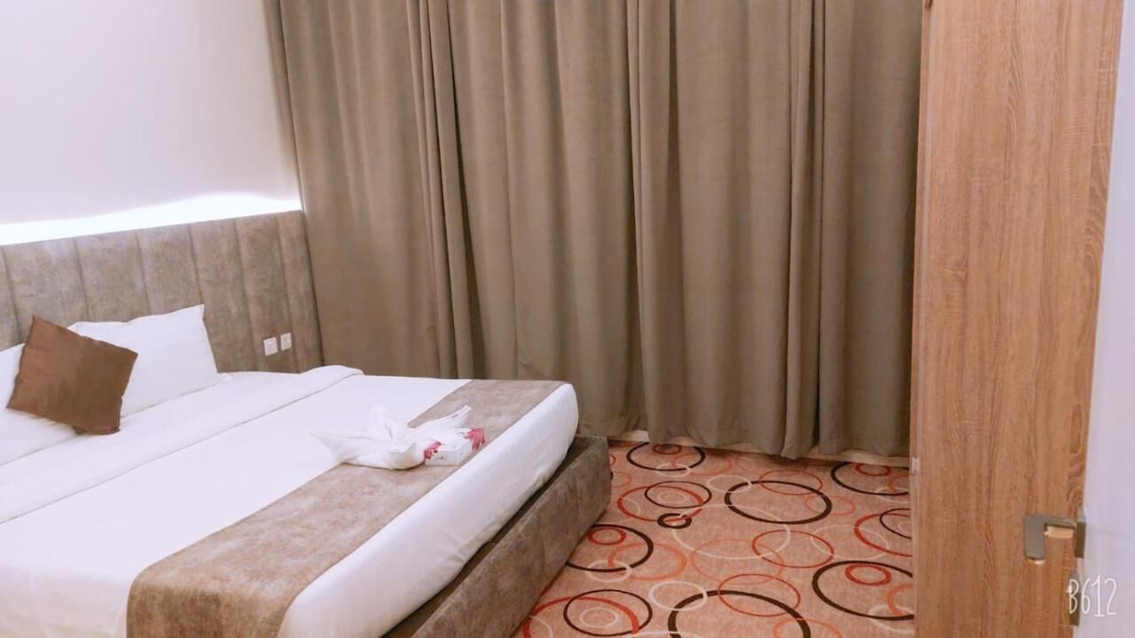 Una habitación de hotel con cama, cortinas y alfombra estampada.