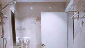 Une salle de bain moderne avec un sol en marbre, des toilettes, un lavabo avec un miroir et un espace douche.