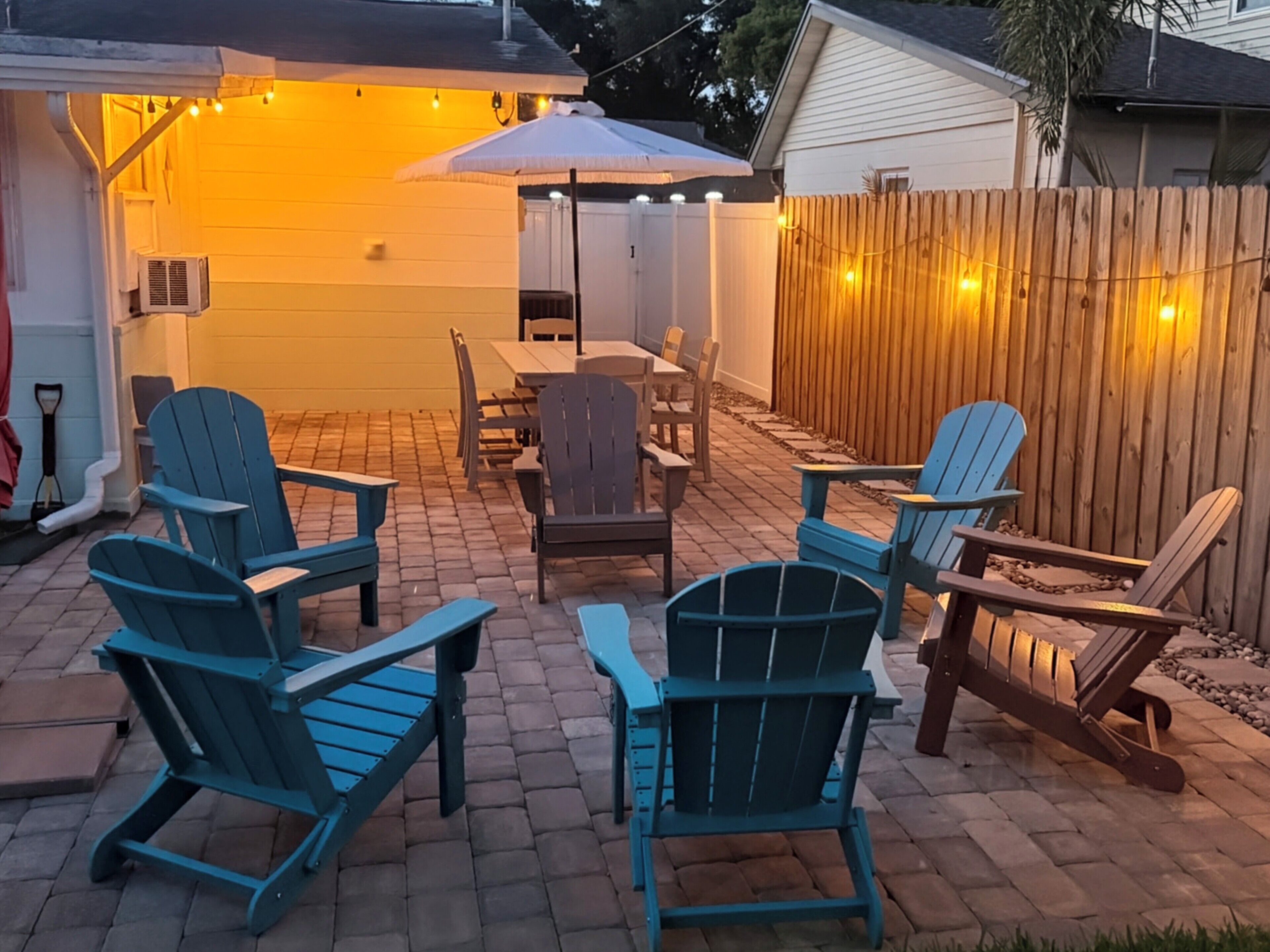A patio with Adirondack chairs, a table, and an umbrella.