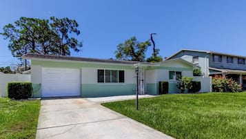 A single-story house with a garage, a front lawn, and a tree in the background.
