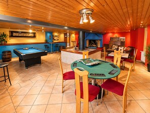 A pool table, bar area, and seating with a fireplace.