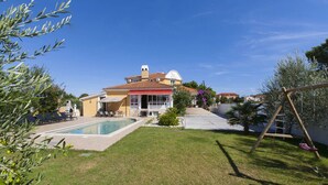 Ein Haus mit Swimmingpool, Terrasse und Schaukel.